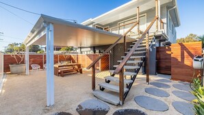 A modern house with a covered patio, a wooden staircase, and a garden area. - The Pacific Pearl,16 Pacific Avenue, Anna Bay - pet friendly, air con (Anna Bay)