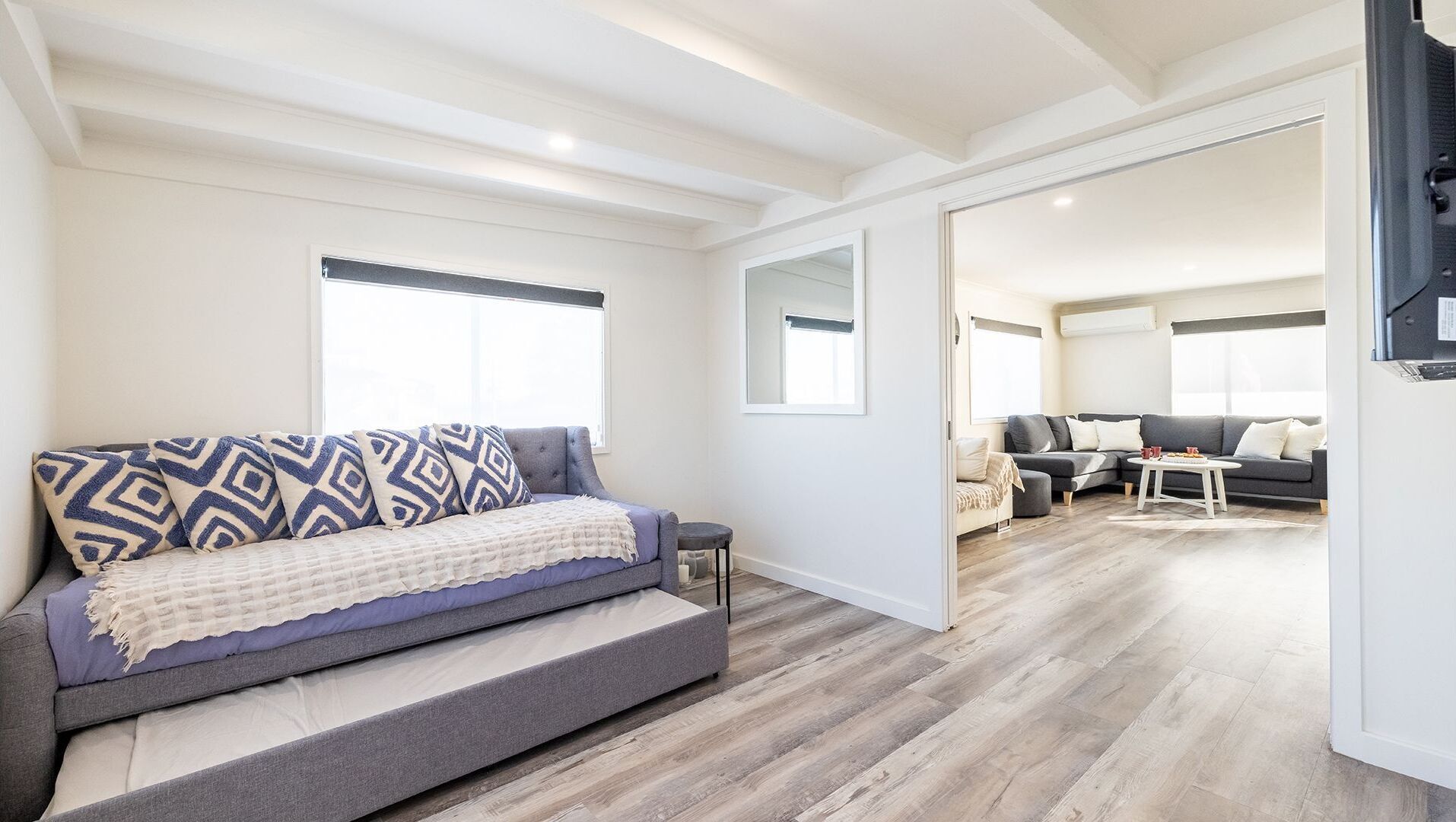 A modern living room with a grey sofa, a coffee table, and a grey couch in the background.