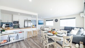 A modern kitchen with white cabinets, a built-in oven, and a stainless steel refrigerator. - The Pacific Pearl,16 Pacific Avenue, Anna Bay - pet friendly, air con (Anna Bay)