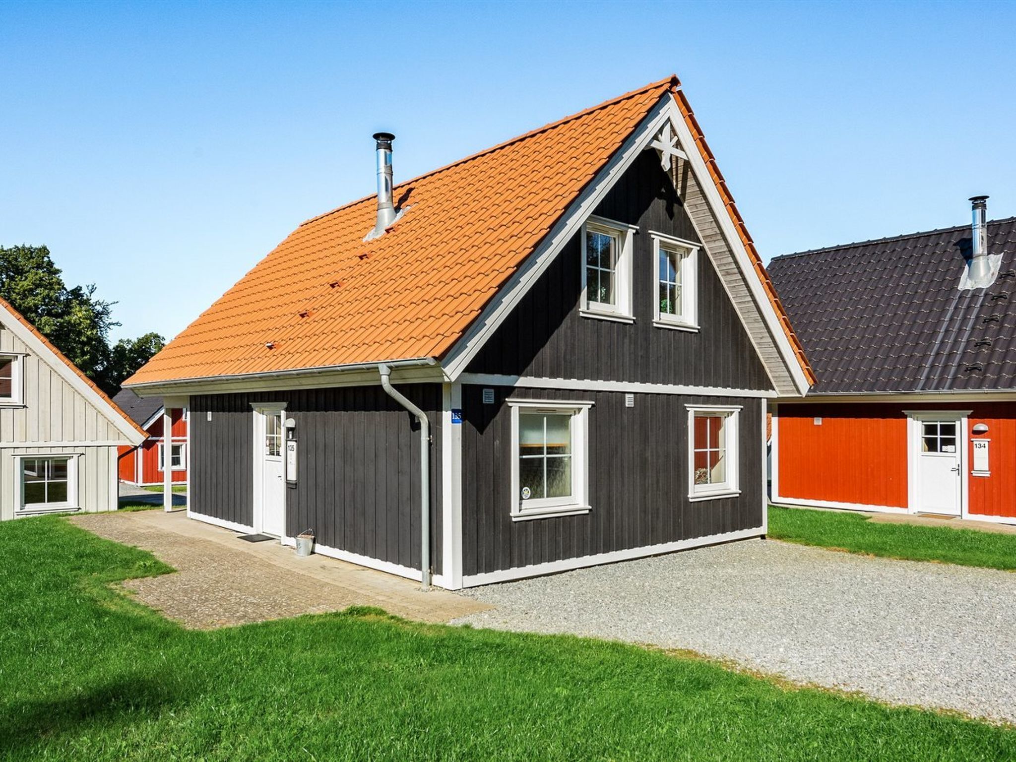 A modern two-story house with a steeply pitched roof, a chimney, and a well-maintained lawn.