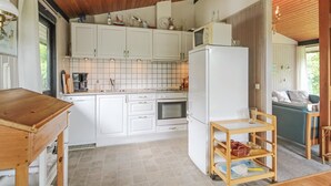 Une cuisine avec des meubles blancs, un plafond en bois et une petite table en bois sur laquelle est posé un plateau.