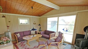 A cozy living room with a wooden ceiling, two sofas, a coffee table, and a fireplace.