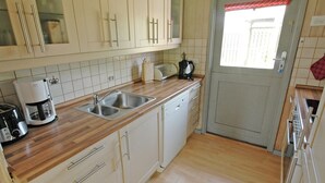 A kitchen with wooden countertops, stainless steel appliances, and white cabinets.
