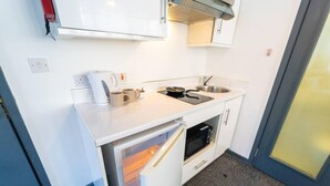 Une petite cuisine équipée d’un four encastré, d’un four à micro-ondes et d’un évier.