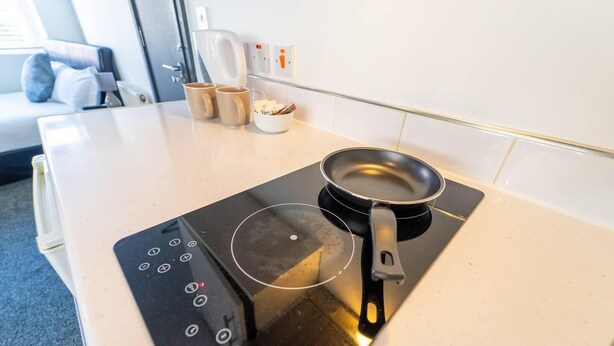 Une cuisine moderne équipée d’une plaque de cuisson à induction, d’une poêle et d’une machine à café.