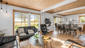 A spacious living area with a black leather sofa, a round coffee table with fruit, and a dining area with chairs and a table. - "Adelia" - 850m to the fjord by Interhome (Tarm)