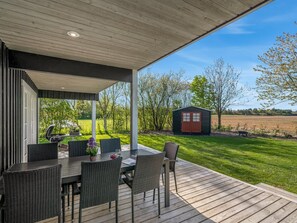 An outdoor patio with a table and chairs, a grill, and a view of a green field and trees. - "Adelia" - 850m to the fjord by Interhome (Tarm)