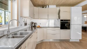 A modern kitchen with wooden ceiling, stainless steel appliances, and a large window. - "Adelia" - 850m to the fjord by Interhome (Tarm)