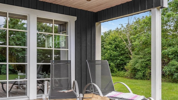 A covered outdoor area with a wooden deck, two lounge chairs, and a table with chairs. - "Adelia" - 850m to the fjord by Interhome (Tarm)