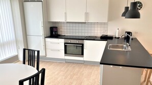 Een kleine keuken met witte kastjes, een zwart aanrecht en een roestvrijstalen spoelbak.