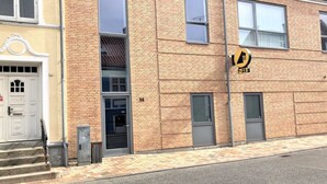 Een gebouw met twee verdiepingen en een bakstenen gevel, genummerd 14, met een groot raam en een deur voorzien van een klein raam erboven.