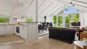 Una cocina amplia con armarios blancos y un comedor con sillas negras.
