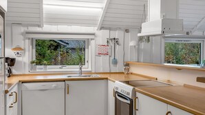 Una cocina moderna con armarios blancos, encimera de madera, lavavajillas Bosch y horno.