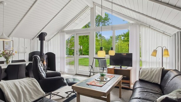 Una sala de estar moderna con chimenea, muebles de cuero y ventanas amplias que ofrecen vistas al verdor.