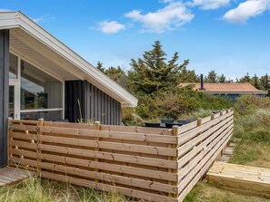Een modern huis met een houten terras en een groot raam.