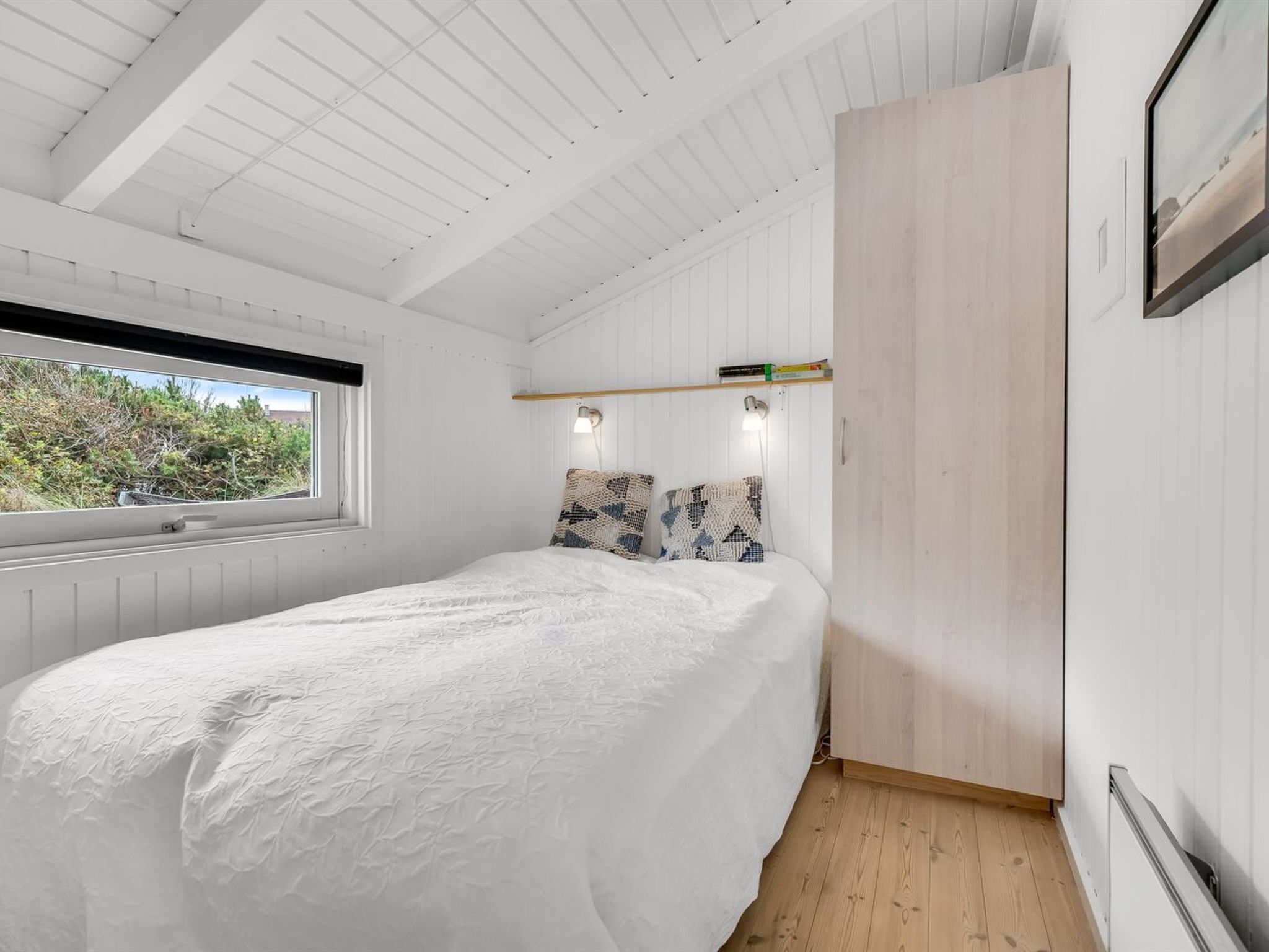 Une chambre à coucher avec un lit, une fenêtre, une armoire et une étagère remplie de livres.