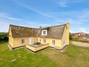 A yellow house with a thatched roof, a small porch, and a garden area. - "Urte" -  from the sea by Interhome (Ringkøbing)