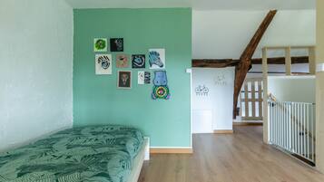 Una stanza con un letto, una scala e un muro decorato con disegni per bambini.