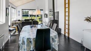 Een moderne eetruimte met een grote tafel, stoelen en hanglampen.