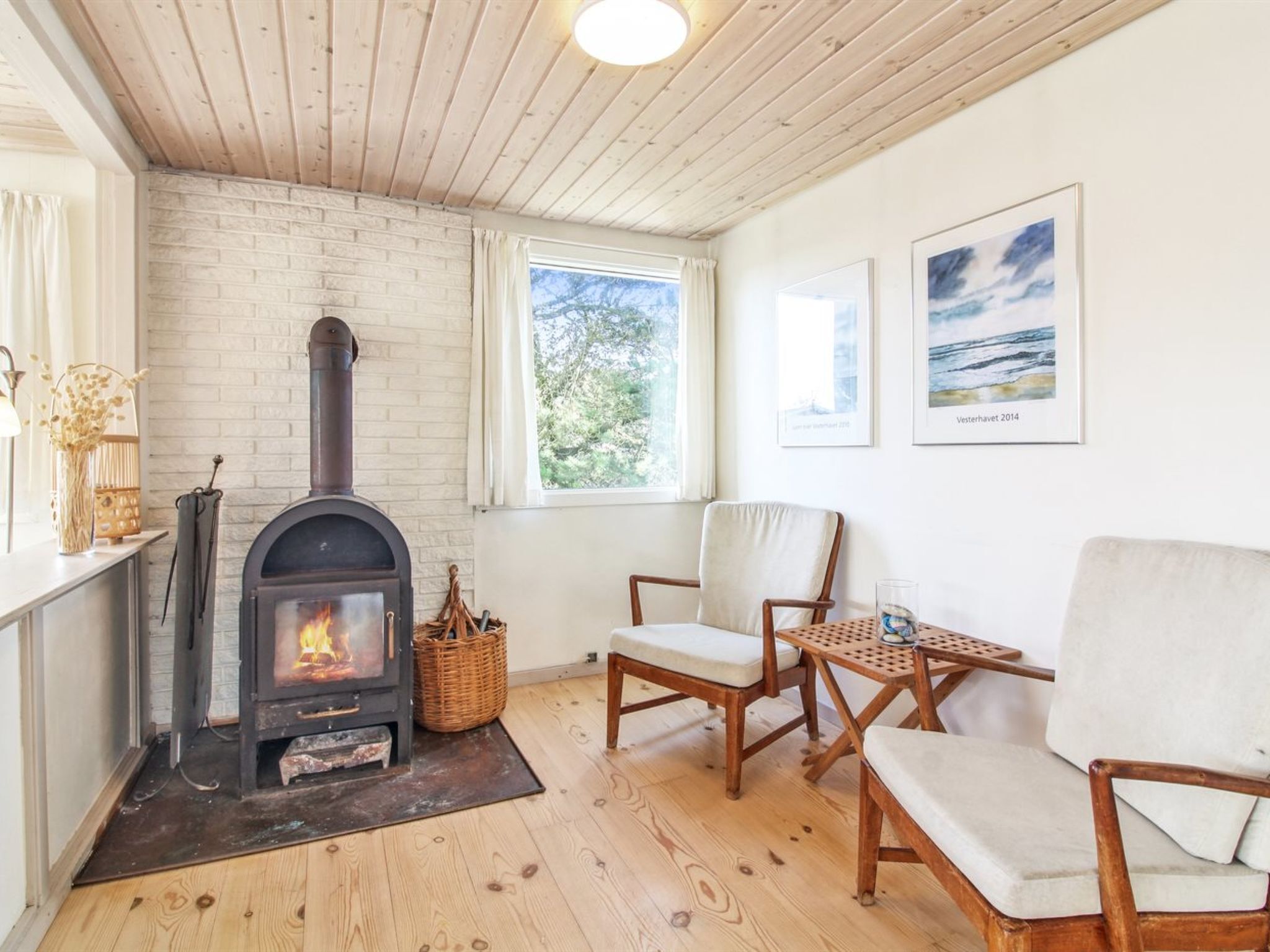 Una habitación acogedora con chimenea, suelo de madera y dos sillones.