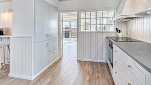 A modern kitchen with white cabinetry, a wooden floor, and a large window.