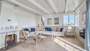 A spacious living room with a fireplace, a sofa set, a coffee table, and a dining area.