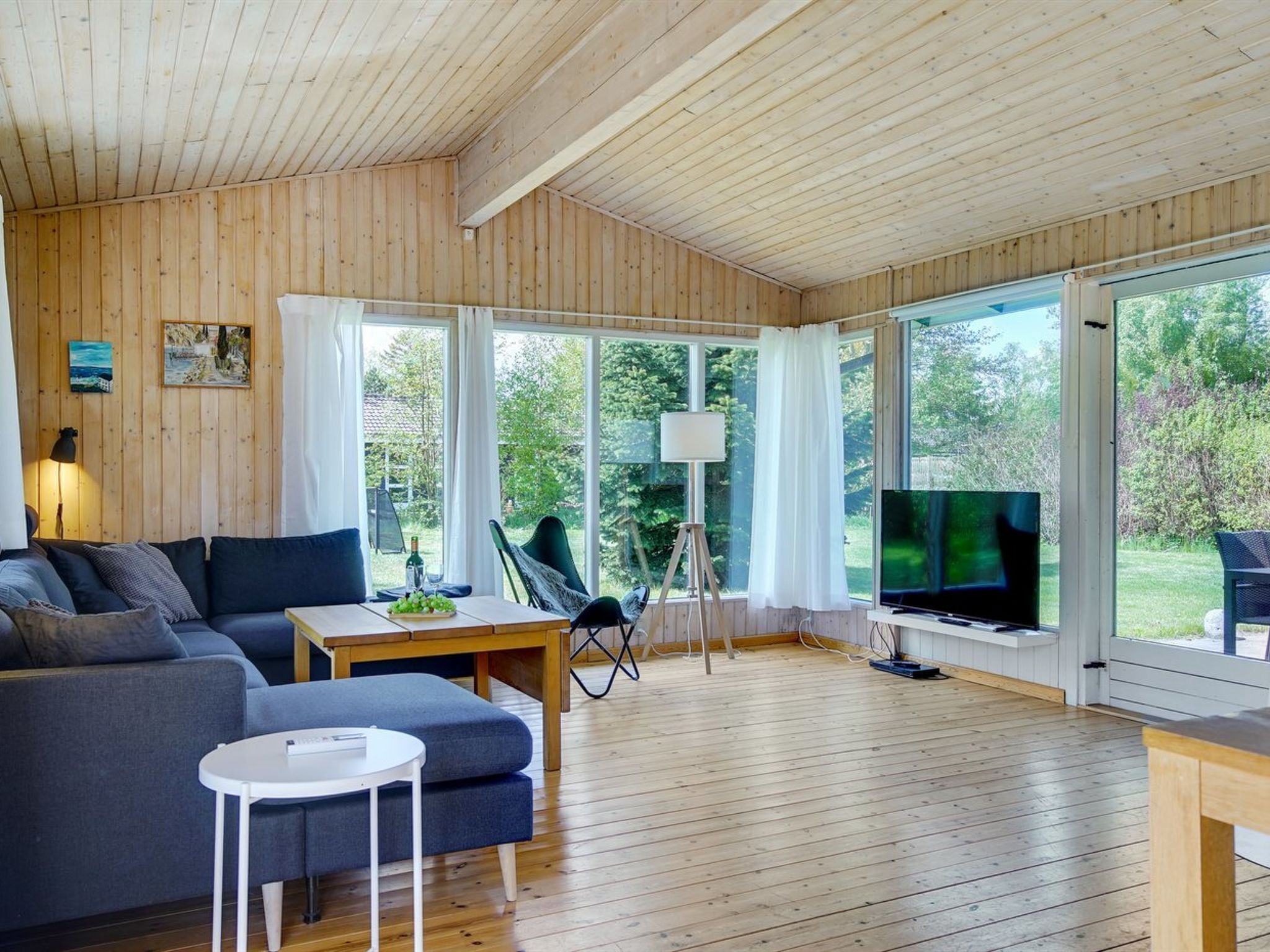 A spacious living area with a wooden floor, a sofa, a small table, and a TV.