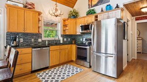 A kitchen with wooden cabinets, a stainless steel refrigerator, a microwave, and a dishwasher. - 16 mi to DT, Hot Tub, Fire Pit, FP, Basket Ball Court, Mt View, Secluded & Quiet (Barnardsville)