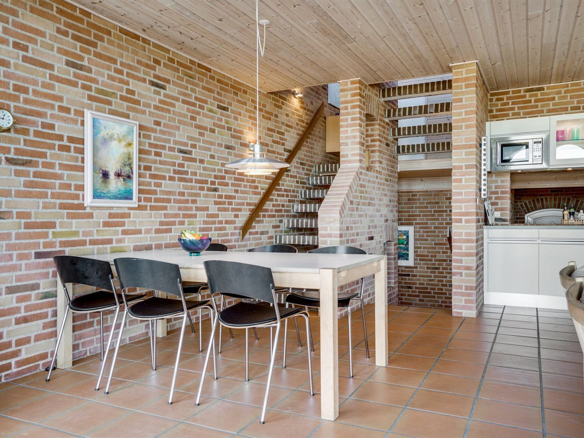 Ein Essbereich mit Backsteinwand, Holzboden und einer Treppe, die zu einer oberen Ebene führt.