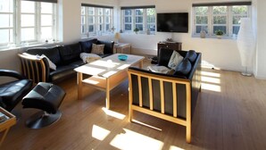 Ein geräumiges Wohnzimmer mit Sofa, Couchtisch und Fernseher.