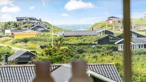 Een kustwoongebied met moderne huizen, uitzicht op zee, en een raam met twee flessen.