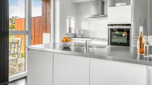 Een moderne keuken met witte kasten, een roestvrijstalen spoelbak en een ingebouwde oven.