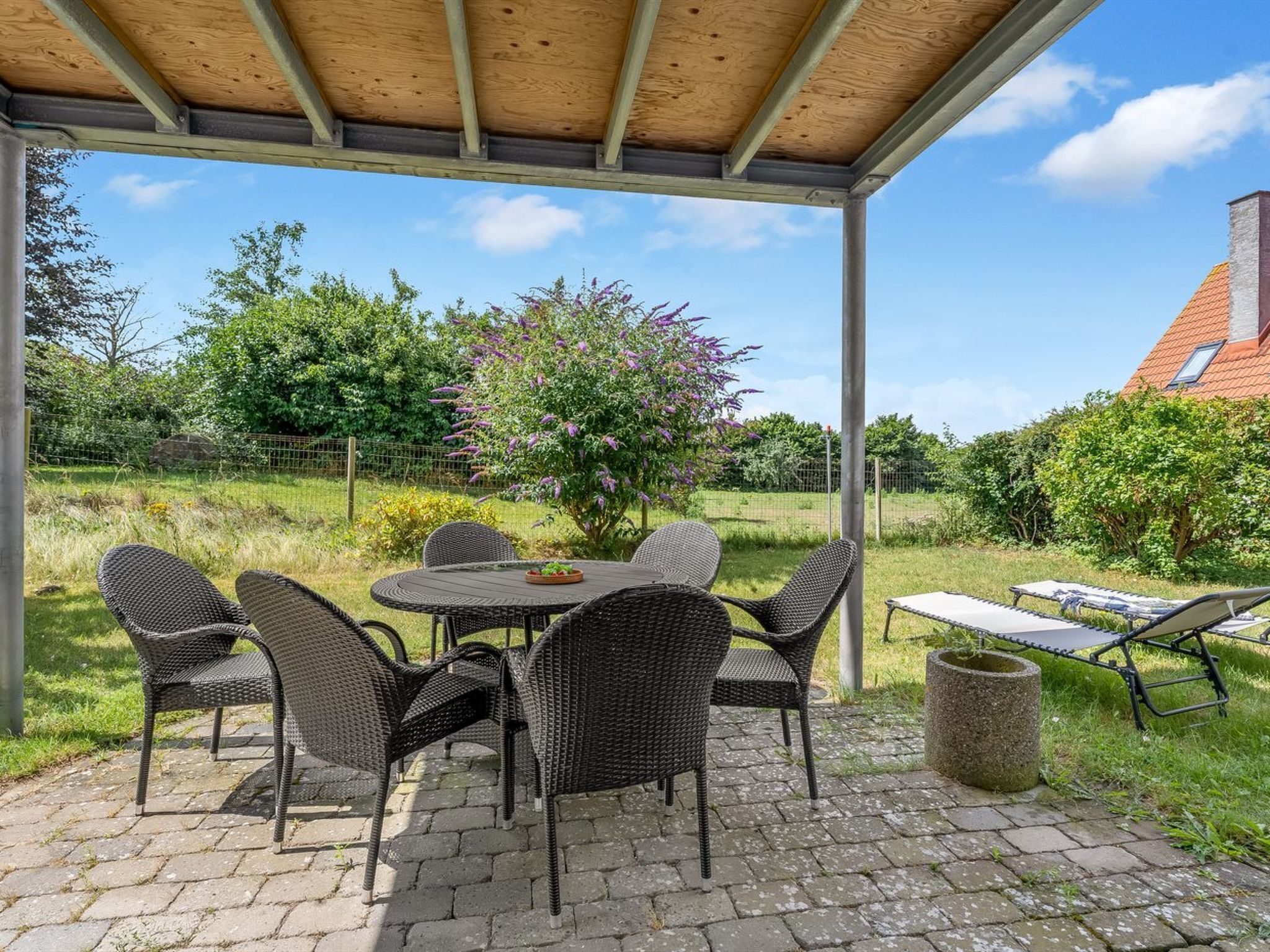 En udendørs patio med overdækket siddeområde, et bord og stole.