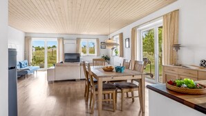 Amplia sala de estar con techo de madera, una mesa de comedor con sillas, un sofá y un televisor.