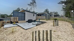 Ett modernt bostadsområde med flera hus, där varje hus har ett garage, en uteplats och en sandig markyta.