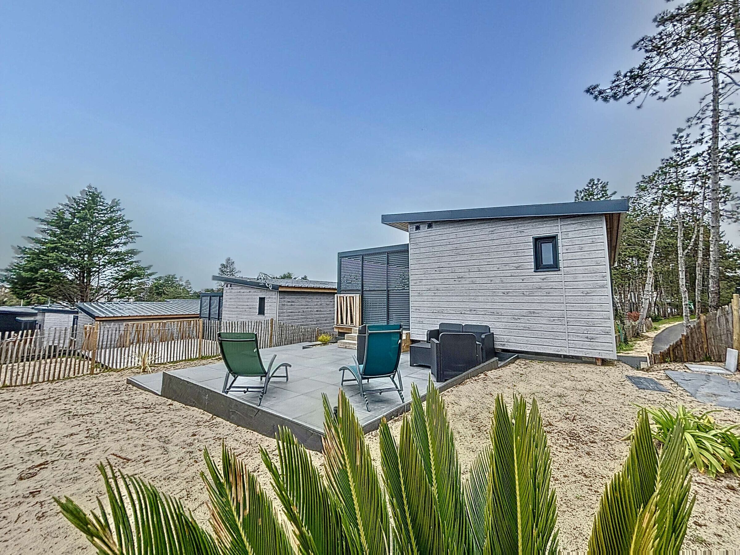 A modern outdoor area with a patio, seating, and a small building.