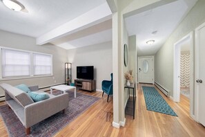 Una sala de estar moderna con un sofá, televisor y una mesita.