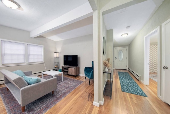 A modern living room with a sofa, TV, and a small table.