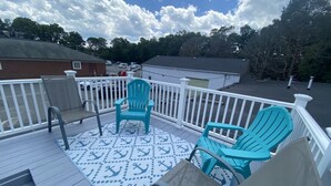 Une terrasse avec des chaises, un tapis à motifs et une rambarde blanche.