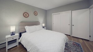 Une chambre à coucher comprenant un lit, des tables de chevet, une tête de lit, deux éléments de décoration murale et une armoire.