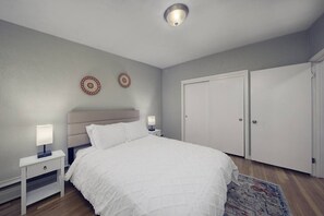 Une chambre à coucher comprenant un lit, des tables de chevet, une tête de lit, deux éléments de décoration murale et une armoire.