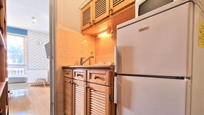 Une cuisine compacte avec des meubles en bois, un évier encastré et un réfrigérateur blanc.