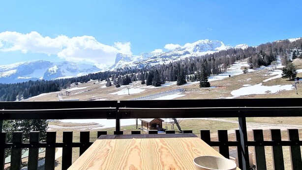 Une terrasse en bois offrant une vue sur des montagnes enneigées et un ciel dégagé.