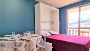 Une chambre avec un lit, une table avec des chaises et une fenêtre donnant sur un paysage montagneux.