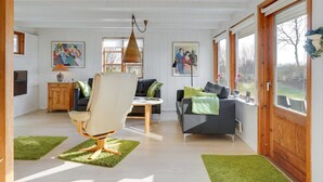 Amplia sala de estar con techo alto, comedor y un gran ventanal con vistas al exterior.