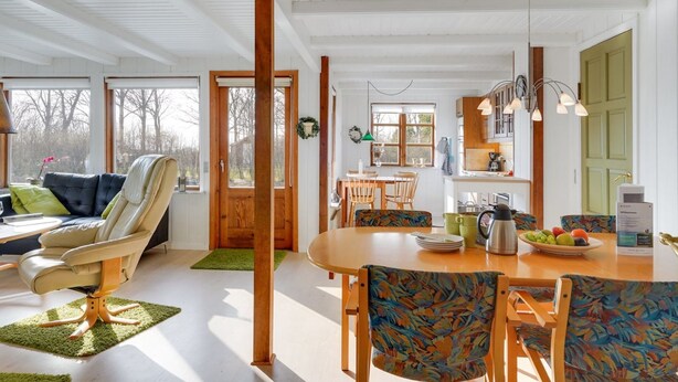 Amplia sala de estar con sofá, una mesa de comedor con sillas y una cocina al fondo.