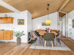 Uma cozinha moderna com armários de madeira, uma área de refeições com mesa e cadeiras, um lustre e uma lareira.