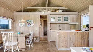 Interior de madera con comedor, cocina y una ventana.