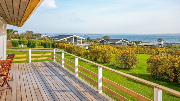 Una terraza de madera con vista al mar y casas al fondo.