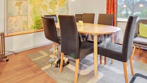 A dining area with a round table, six chairs, a large map on the wall, and a window with curtains. - "Claudia" by Interhome (Bredebro)